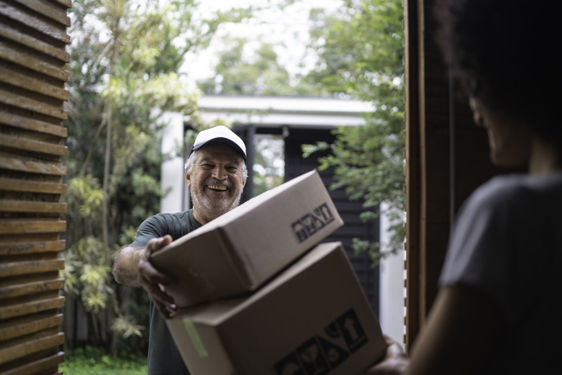 A parcel delivery service delivers packages to a young man at his doorstep.